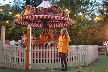 a girl stands near the carousel