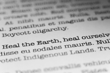 Fototapeta premium Heal the Earth, heal ourselves. Text printed on a page. A piece of paper with a phrase written in retro typewriter font.