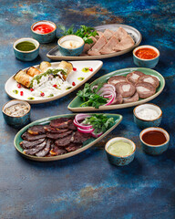 The bowls are filled with different kinds of food, including various meat appetizers, vegetable appetizers, and sauces. A table with many bowls of food on it.