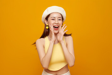 Young Asian teen woman shout announce discount isolated on yellow background. Speech and...