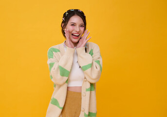 Young Asian teen woman shout announce discount isolated on yellow background. Speech and...