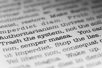 Trash the system, not the soil. Text printed on a page. A piece of paper with a phrase written in retro typewriter font.