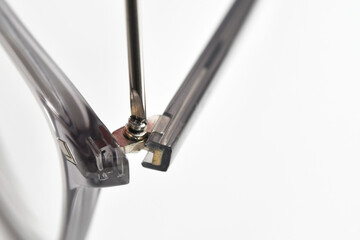 Close up view of a small screwdriver being used to tighten the screw on the arm of a pair of...