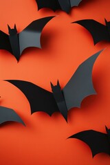 Naklejka premium Halloween themed background with black paper bats on orange surface in a flat lay arrangement for festive mood