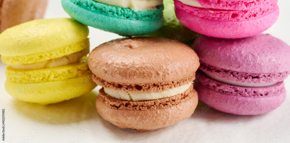 Poster an assortment of colorful macarons on a white surface. the macarons have a smooth, delicate shell an