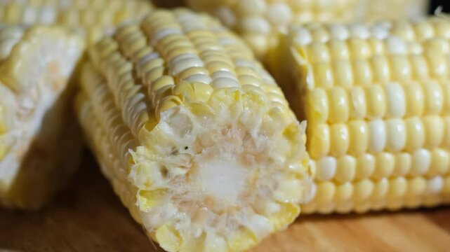 The image shows several pieces of corn on the cob that have been cut into short segments. The kernels are plump, glossy, and golden yellow, arranged in tight, uniform rows.