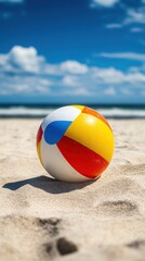 Obraz premium Colorful beach ball resting on sandy shore under bright blue sky summer vacation joy and seaside relaxation