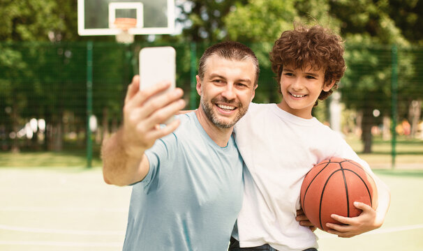 Happy Loving Family. Excited father taking selfie with his son, basketball player holding ball