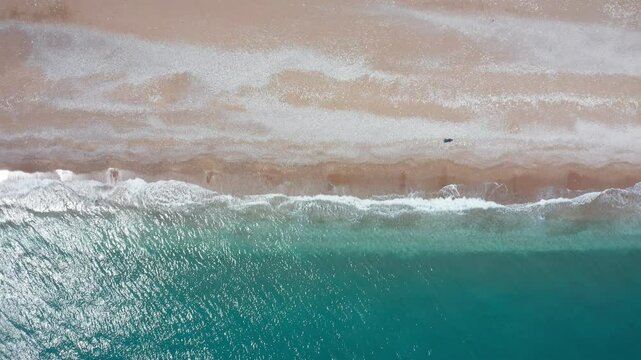 Drone image of Olympos beach, famous for its historical and natural beauties in Antalya. Flying parallel to the shore, the drone captures the moment when the turquoise sea meets the golden sand.