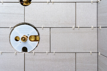 Corner of a shower renovation install showing tile spacers before grouting and cutout hole for the main shower fixture