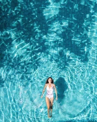 Fototapete Rund Woman floating and relaxing in a clear blue swimming pool © Néstor