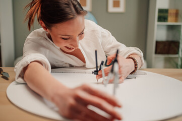 Female architect designing using compass on blueprint in home office