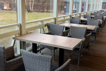 Outdoor cafe seating with modern wicker chairs and wooden tables on a terrace