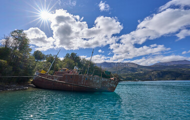 Abandoned ship in General Carrera Lake in Chile - remains of the closed mining industry. A ship located in a way of the boat tour to Marble Caves, attraction in the region. Rays radiating from the sun
