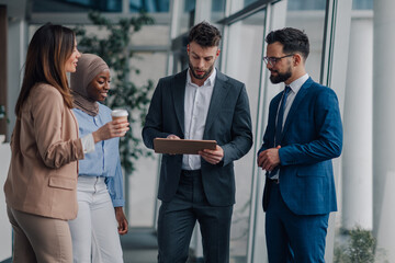 Business people discussing work using tablet in office hallway