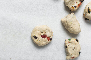 Hot cross bun dough being cut into pieces on a marble countertop, process of making hot cross buns