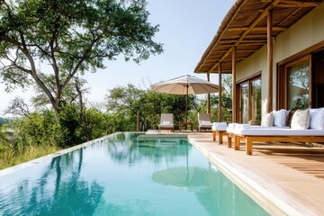 Obraz premium A serene poolside view featuring a modern villa with a thatched roof, surrounded by lush greenery and an umbrella for shade.
