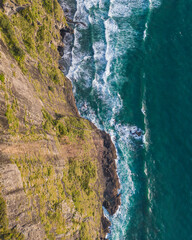 Fototapeta premium Aerial View of Dramatic Coastal Cliffs and Ocean Waves, Mercer Bay, Piha, New Zealand