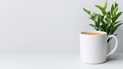 A white ceramic mug filled with coffee sitting on a minimalist white surface, accompanied by a small green plant, and serene and simple composition.