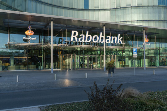 Modern glass Rabobank headquarters office building in the Netherlands, with large logo and clear entrance, reflecting urban architecture.