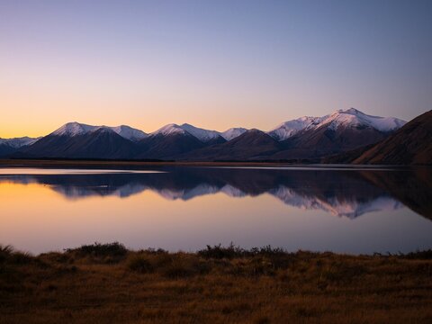Lake Heron idyllic calm serene golden hour mountain peak winter sunset mirror reflection, Southern Alps landscape at Ashburton Lakes New Zealand