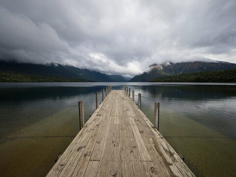 Wooden jetty pier dock at Saint Arnaud Lake Rotoiti, Nelson Lakes National Park Southern Alps mirror reflection alpine landscape , Tasman New Zealand