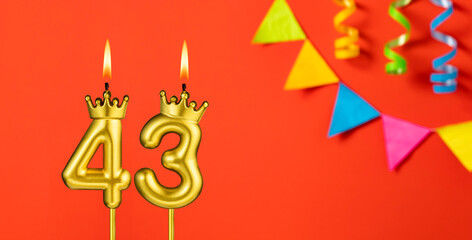 Number 43 candle - Birthday celebration on an orange background with pennants
