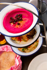 Traditional Mediterranean appetizer set Mezze trio of polenta with fried bacon and feta cheese, beetroot hummus and fried cauliflower served with warm pita
