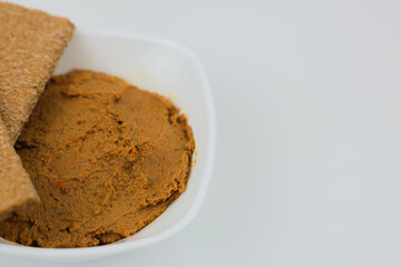Close-up of a white plate with liver pate and bread on top on a white background with space for text. The concept of snacks, healthy food, diet.