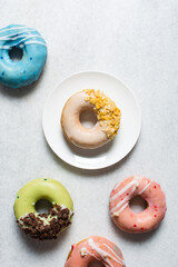 Overhead view of glazed donuts on a white countertop, top view of homemade pastel doughnuts, process of making Easter glazed doughnuts