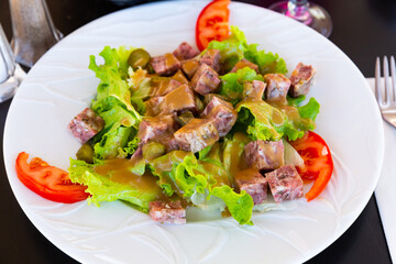 Traditional French cuisine, salad with chopped headcheese, fresh lettuce leaves, pickled cucumbers and tomatoes