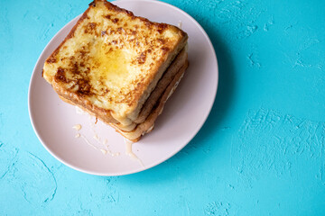 Close-up of buttered french toast with syrup and honey on pink plate
