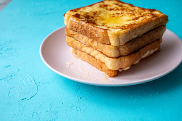 Close-up of buttered french toast with syrup and honey on pink plate