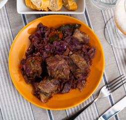 Appetizing spicy baked pork ribs with vegetable garnish of braised red cabbage on plate