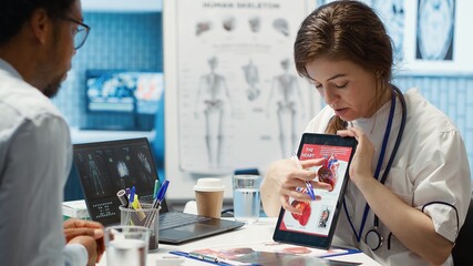 Woman specialist explaining heart function and condition on test results, doctor patient...