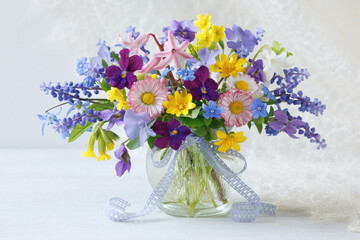 Spring still life with a bouquet of flowers pansies, omphalodes , hyacinth, primroses, scilla, muscari and periwinkle in a vase on the table, beautiful card.