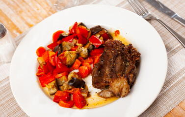 Baked pork cheek is seasoned with spices and garlic. Meat is complemented with stewed vegetables and sprig of dill.