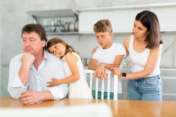 Wife with son and daughter calm down upset father after quarrel