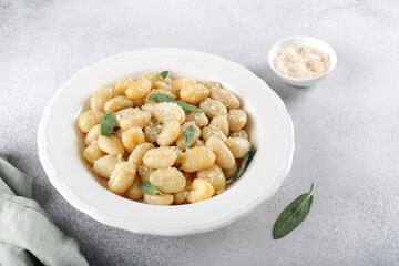 Traditional Italian potato gnocchi with butter, sage, cheese on gray background. Italian food.