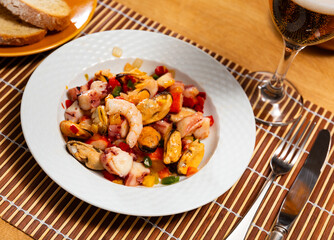 Close-up of plate filled with salpicon, salad of seafood and pickled vegetables. In restaurant, guest was served seafood tapas salpicon snack