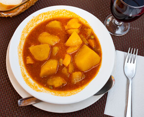 Restaurant serves dish of stewed potatoes with cuttlefish. Vegetable stew made from potatoes, green peas, carrots and shellfish.