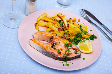 Tasty grilled salmon fillet with french fries and slice of lemon