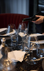 Champagne tasting, Wine glasses are on the table, stylish table setting, wine is poured from a bottle and decanter, sparkling wine bubbles, snacks, people smell the aroma and taste the wine