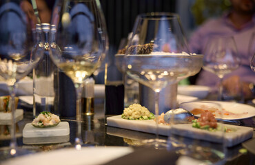 Champagne tasting, Wine glasses are on the table, stylish table setting, wine is poured from a bottle and decanter, sparkling wine bubbles, snacks, people smell the aroma and taste the wine