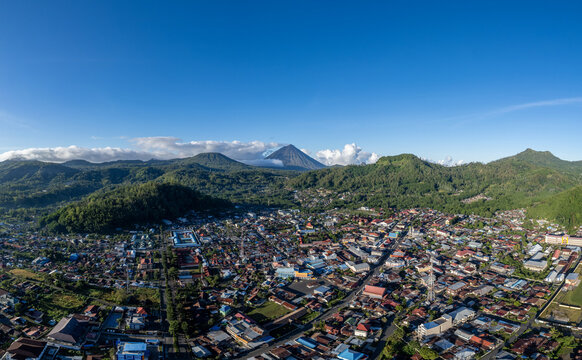 Beautiful panoramic aerial photo of Bajawa town with Mount Inerie towering in the background, surrounded by lush green hills in Flores, East Nusa Tenggara, Indonesia.