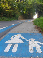 View of the road with blue markings, mother and child on the pedestrian part of the road leading up...