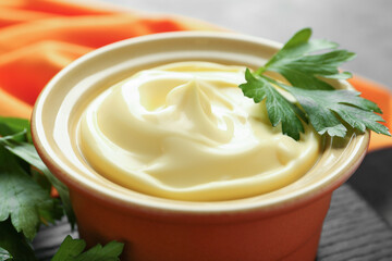 Delicious mayonnaise sauce in bowl with parsley on table, closeup