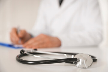 Fototapeta premium Doctor working and stethoscope on table in hospital, selective focus