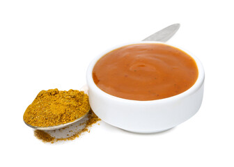 Tasty curry sauce in bowl and spoon with powder isolated on white