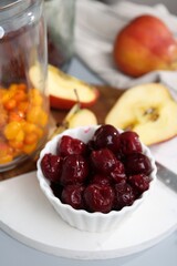 Tasty cherries, apples and sea buckthorn berries on light grey table, closeup